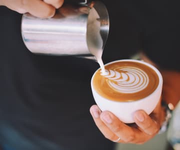 man pouring cream into a cup of coffee