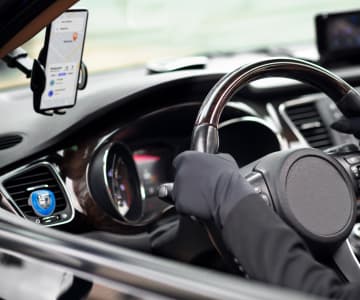 the inside of the car driver's side, a smartphone with an open application - map is fixed on the windshield